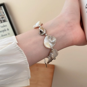 Dettaglio del bracciale con perle e conchiglie con sfere d'argento sul polso