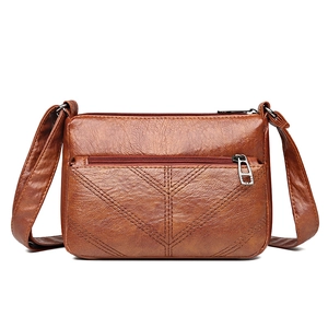 Brown PU leather crossbody bag with V-shaped stitching and adjustable strap on white background