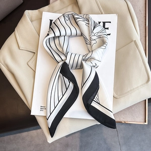 Elegant black and white striped silk scarf with floral pattern tied in a bow on a magazine