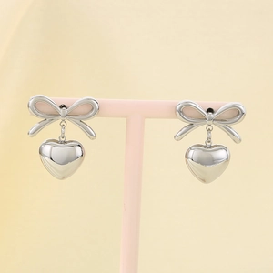Macro detail of silver-tone ribbon bow heart earrings with polished metallic finish