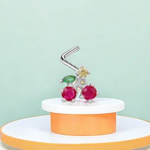 Macro detail of cherry nose stud with red gems and green leaves on a display stand