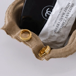 Dettaglio macro di orecchini a cerchio intrecciati placcati oro 18K con zirconi bianchi