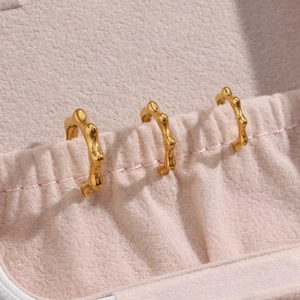 Close-up of three gold earrings with organic bamboo texture in a pink velvet jewelry box