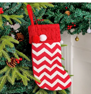 Close-up of a red and white knitted Christmas stocking hanging on a decorated tree