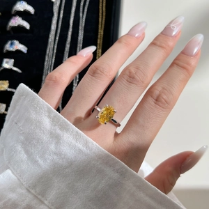 Close-up of an oval-cut yellow gemstone ring featuring a classic four-prong silver setting