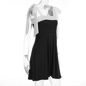 Close-up of contrast bow shoulder straps and bodice detail on black A-line mini dress