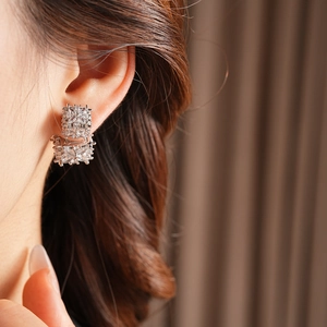Gros plan de boucles d'oreilles carrées en zircon au design géométrique argenté brillant