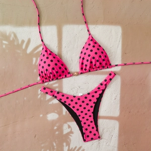 Detail of rose pink bikini top with black polka dots and a golden sun buckle decoration