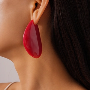 Gros plan d'un mannequin portant la grande boucle d'oreille rouge en résine irrégulière