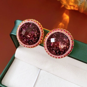 Macro detail of round resin stud earrings with pink crystal border and gold rope texture