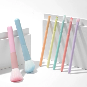 Macro shot of macaron-colored makeup brushes on white geometric stands with soft lighting