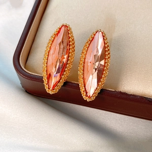 Macro detail of marquise-cut orange crystal earrings with gold beaded trim in jewelry box