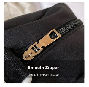 Detail shot of a smooth gold metal zipper on black nylon fabric of a cat canvas bag