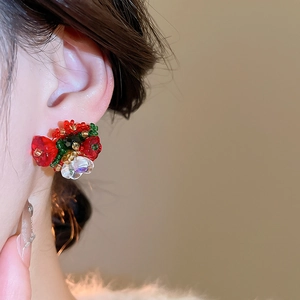 Close-up of handmade beaded floral earrings with red and green crystals on the ear