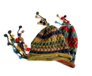 Detail of colorful striped hand-knitted beanies with fuzzy pompom tassels and retro texture