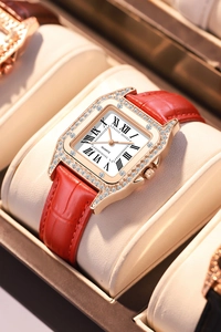 Macro shot of rose gold square watch case with dual crystal bezel and red leather strap