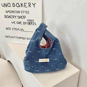 Detail of blue denim tote bag featuring red checkered lining and white bow pattern
