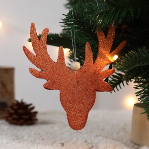 Sparkly orange-red reindeer head ornament hanging on a Christmas tree with warm lights