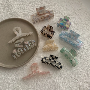 Flat lay of multiple acetate hair claws in various patterns on a ceramic plate