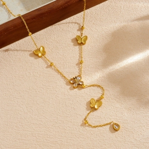 Collier papillon doré avec pendentif goutte en zircone et glands sur une surface texturée