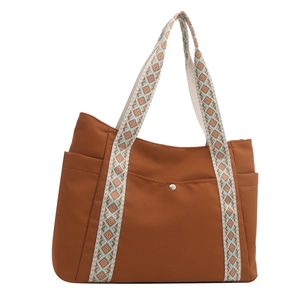 Dettaglio di una borsa tote in nylon marrone con tracolla in tessuto a motivi geometrici