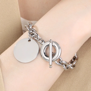 Polished stainless steel OT buckle bracelet with large round pendant on woman's wrist