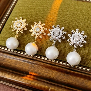 Détails des boucles d'oreilles flocon et perles en or et argent sur velours