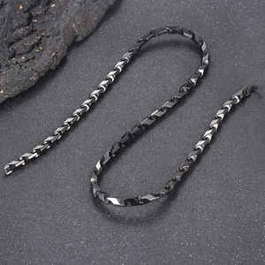 Gros plan d'un collier en acier titane noir avec maillons géométriques sur fond sombre