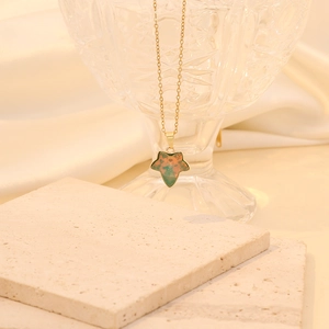 Collier feuille d'érable dorée avec pendentif dégradé vert orange sur fond de pierre
