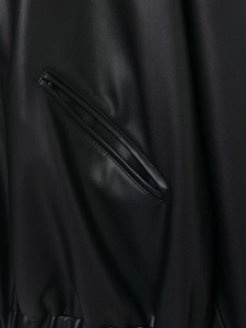 Close-up of black leather jacket featuring detailed pocket stitching and elastic hem