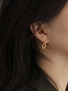 Model wearing gold knot-shaped hoop earrings in 925 sterling silver for a stylish look