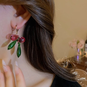 Close-up of sweet cherry crystal drop earrings with green leaves and gold hooks