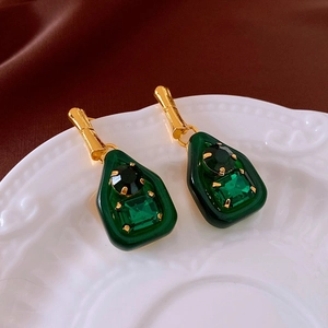 Detail of vintage French court style green teardrop earrings on a white embossed plate