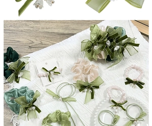 Detail of silk hair scrunchies with white flowers and pearls in green and beige tones