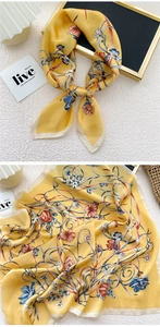 Macro detail of silk scarf featuring bright yellow floral pattern and contrast piping