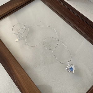 S925 sterling silver heart necklace with blue zircon pendant on beige background