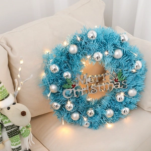 Blue 30cm Christmas wreath with silver ornaments and warm LED lights on a sofa