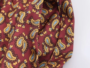 Macro du motif cachemire sur tissu sergé bordeaux montrant les détails de la couture