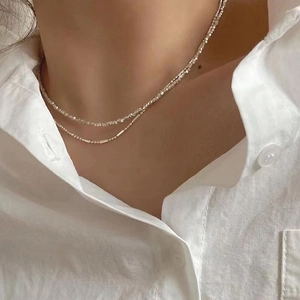 Détail du collier double rang argenté avec chaînes à billes porté sur le cou de femme