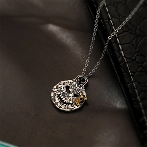 Detail of silver pumpkin pendant with graffiti engravings and tiny gold character model
