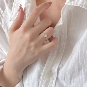 Detail of square zircon ring on hand, minimalist gold finish jewelry for women