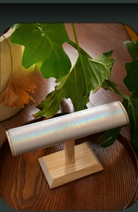 Macro detail of T-bar jewelry stand with silver holographic leather and wood base