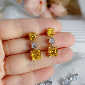 Vue macro détaillée de boucles d'oreilles dorées avec triple zircon cubique carré