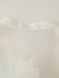 Gros plan sur l'encolure d'un gilet blanc en tissu texturé avec des coutures soignées