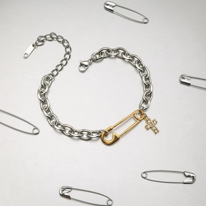 Bracelet trombone en acier bicolore avec épingle de sûreté dorée et pendentif croix