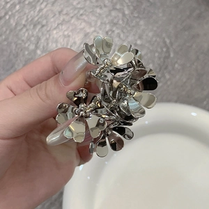 Detailed macro view of silver metallic floral hair clip with 3D heart-shaped petals