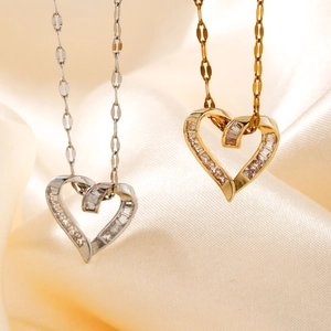 Close-up of gold and silver heart pendants with cubic zirconia on silk background