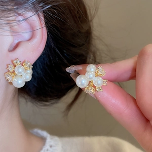 Close-up of elegant gold-plated flower stud earrings with pearls and zircon stones