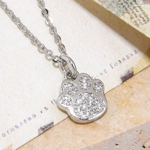 Macro shot of silver cat paw pendant with pavé cubic zirconia on a fine chain necklace