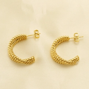 Close-up of 18K gold plated C-shape twisted hoop earrings on light fabric